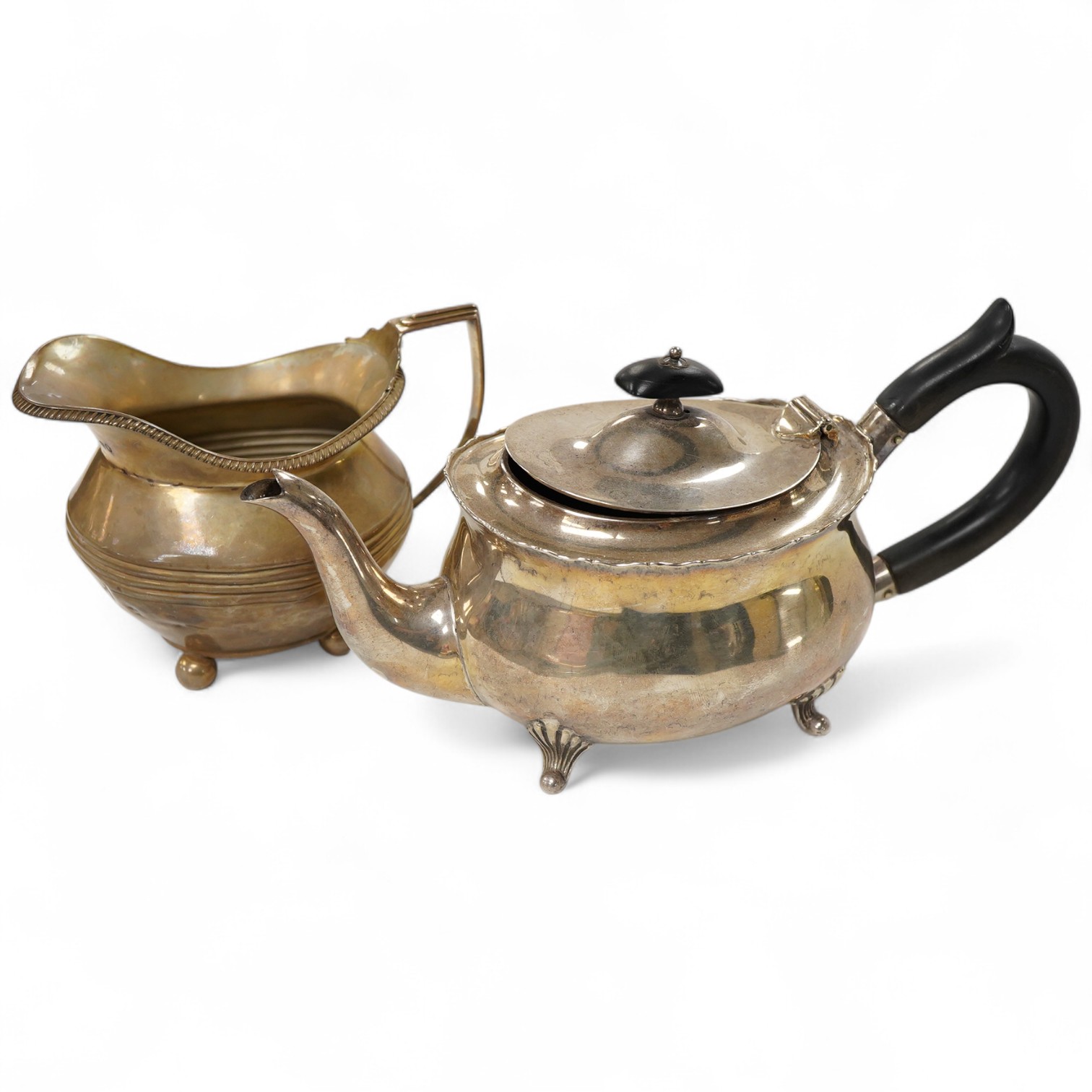 A late Victorian silver oval teapot, William Hutton & Sons, London, 1899, together with a George III silver cream jug, London, 1811, gross weight 15.4oz.